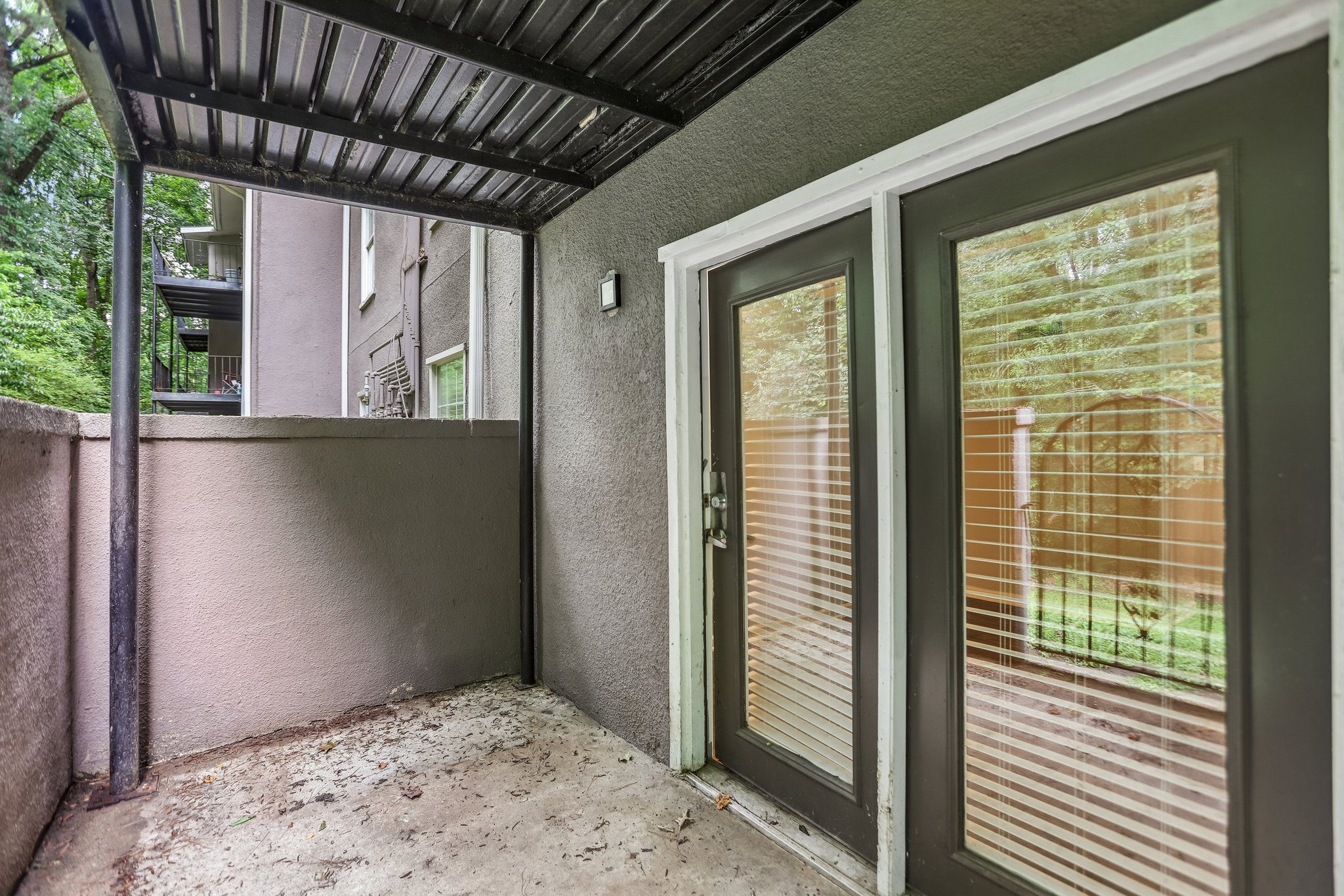 A patio with a sliding glass door and a metal roof.